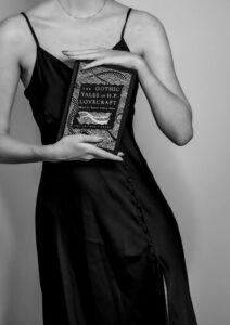 Midsection of a Young Woman Holding a Book by Howard Phillips Lovecraft